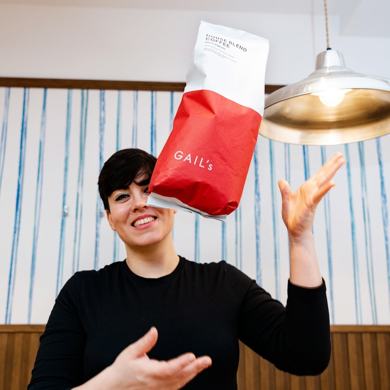 Woman holding a bag of Gail's coffee beans.