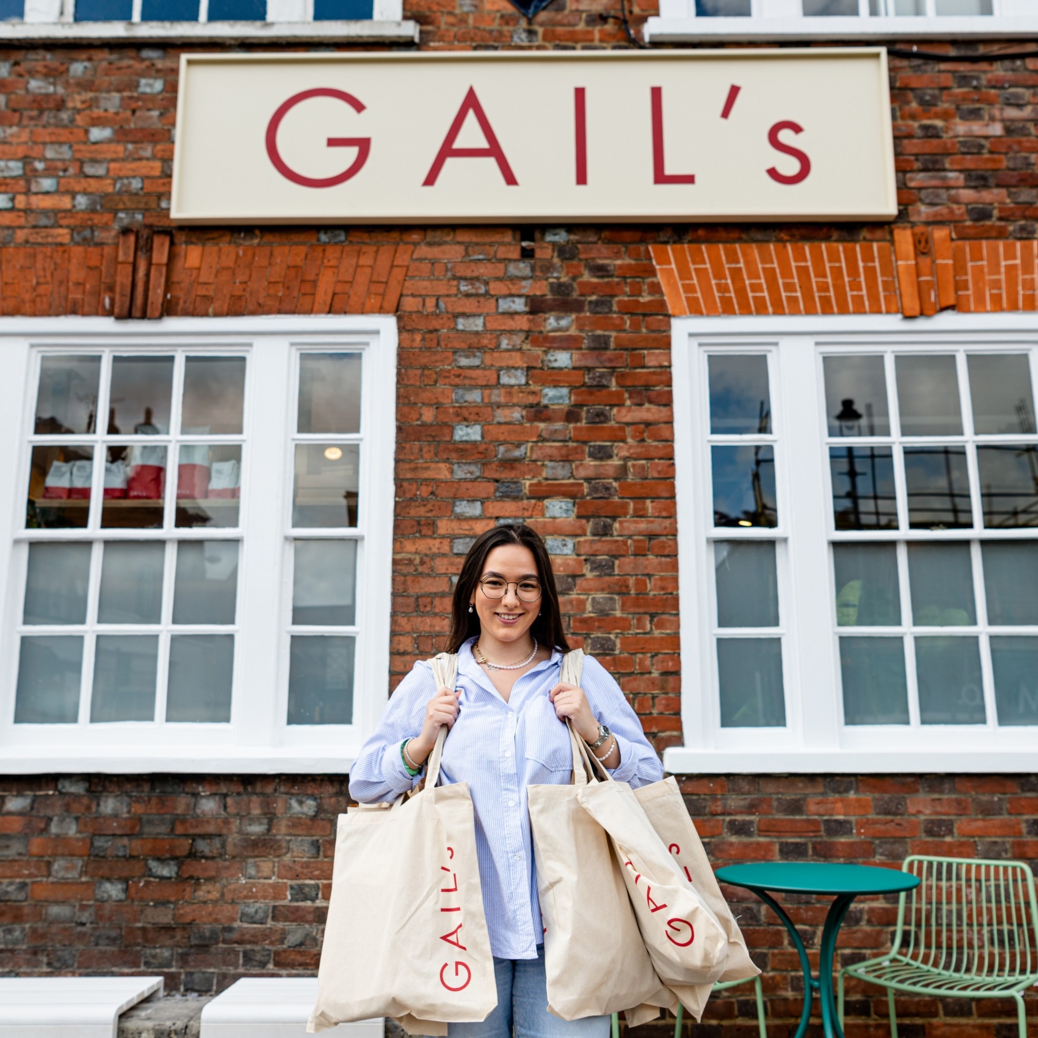 Woman with shopping bags in front of Gail's bakery.