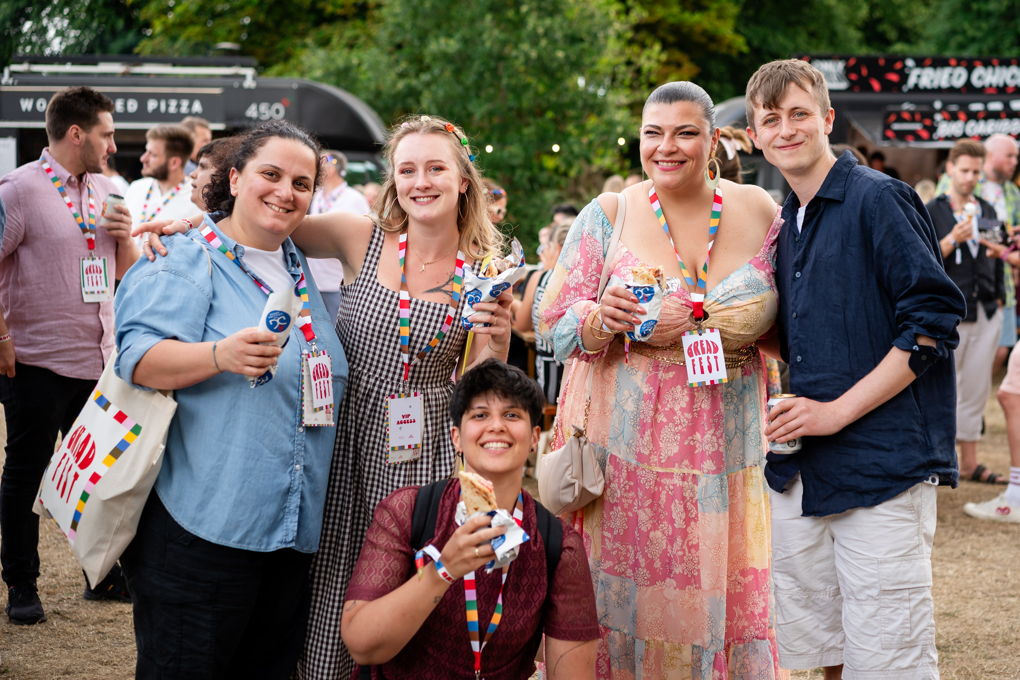 Group of people at an outdoor event, holding food and drinks.
