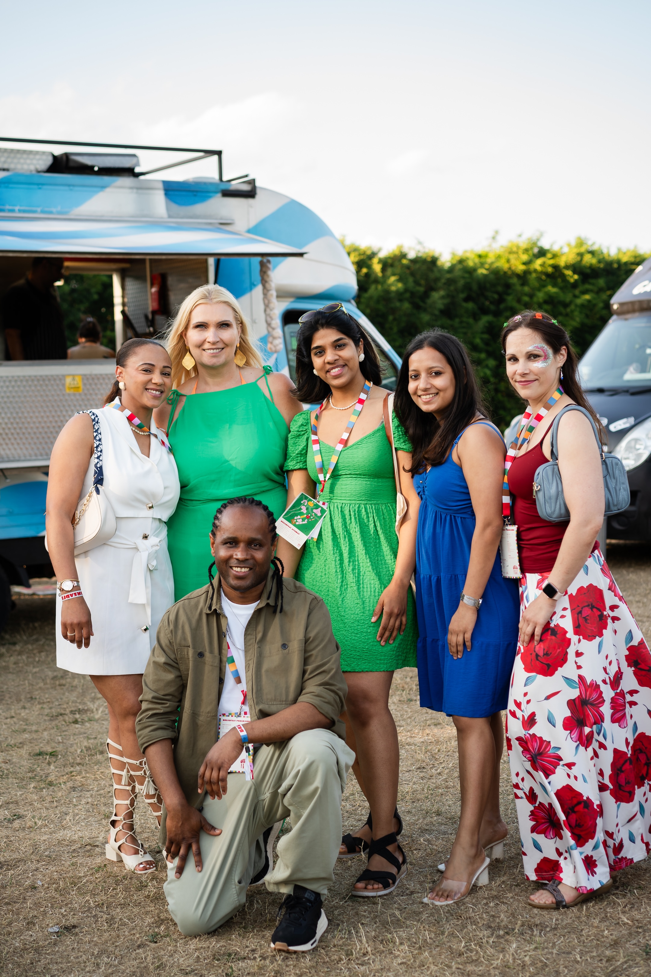 Group of people posing for a photo in front of food trucks.