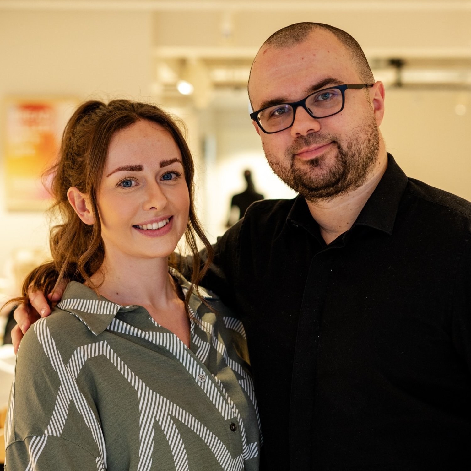 Man with glasses and woman smiling, posing together.