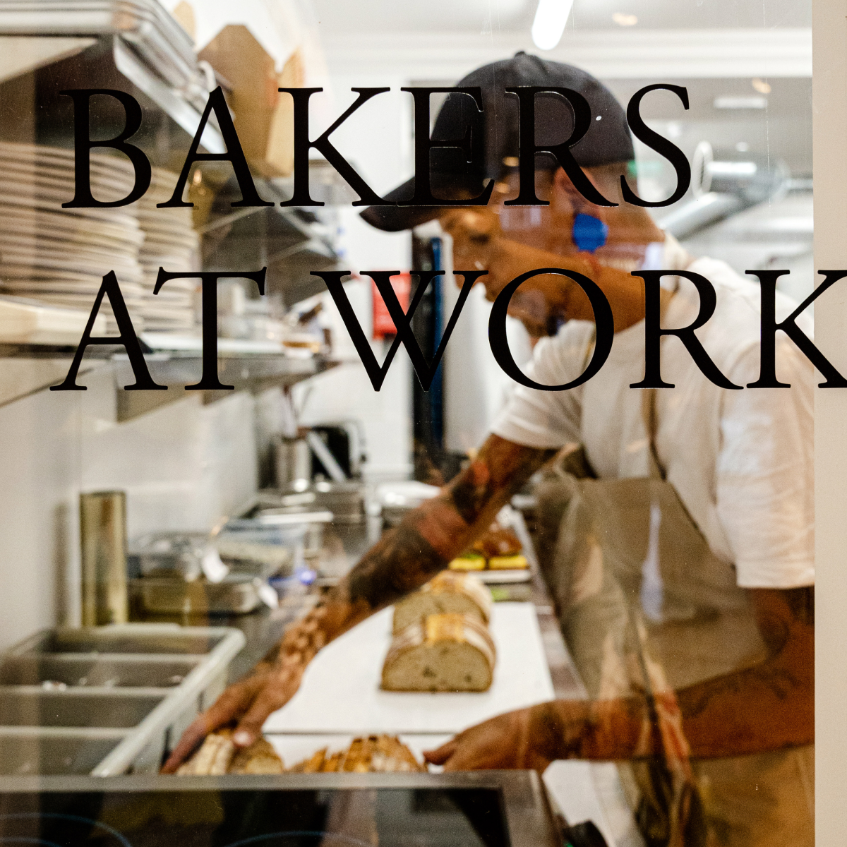 Baker behind glass, with bread and "Bakers at Work" text.
