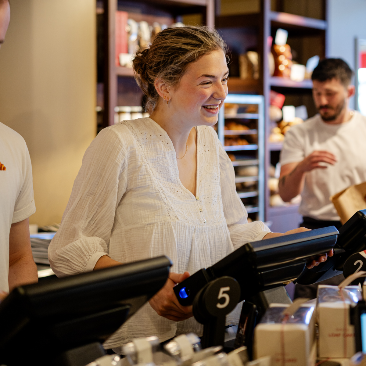 Woman smiling at the counter, other employees in the background.